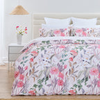 Floral bedding set on a bed in a bedroom with a lamp and flowers on a nightstand.