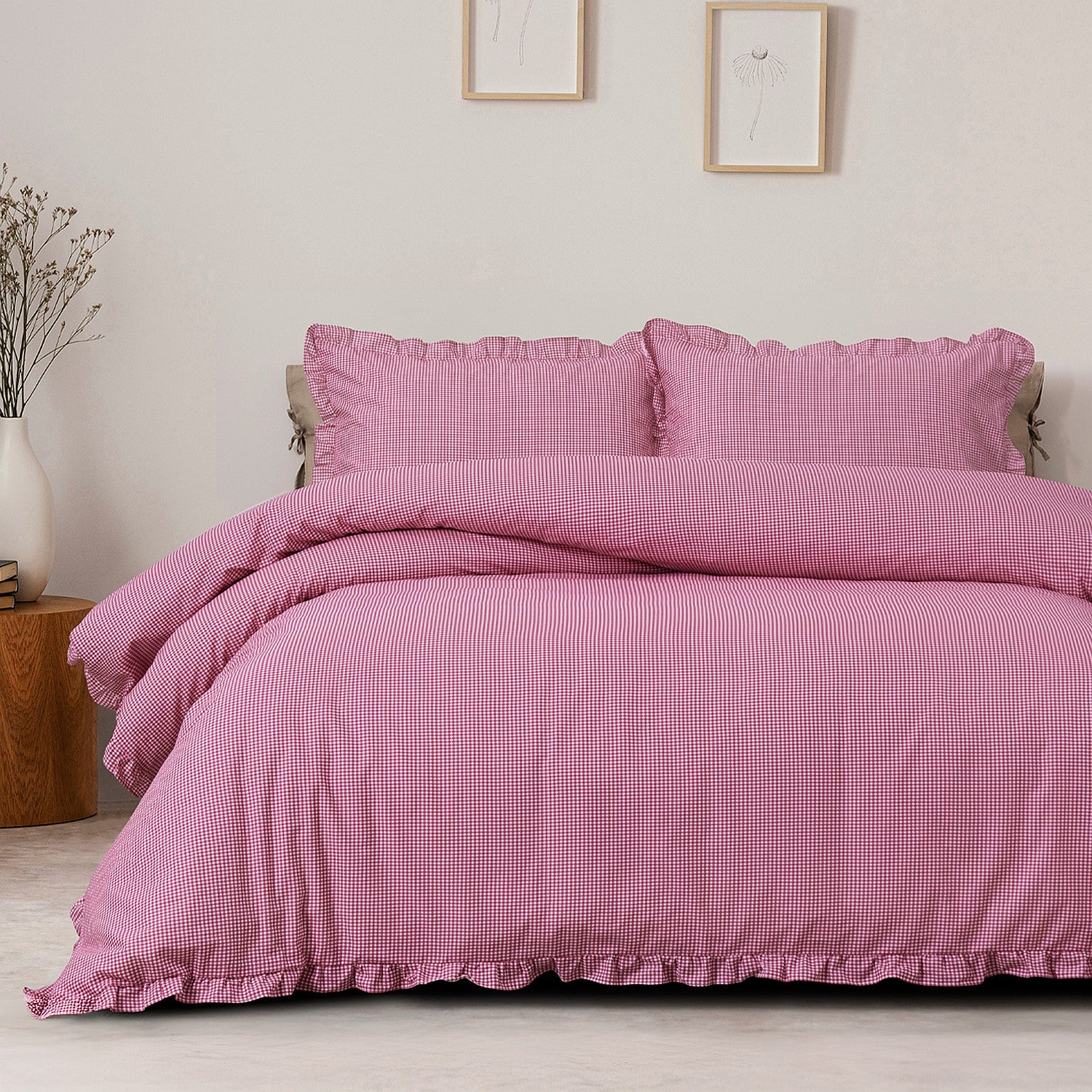 Pink checkered duvet set on a bed in a room with framed pictures on the wall.
