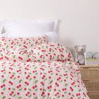 Close up of kids red strawberry print duvet cover set styled on a white bed in a neutral bedroom.
