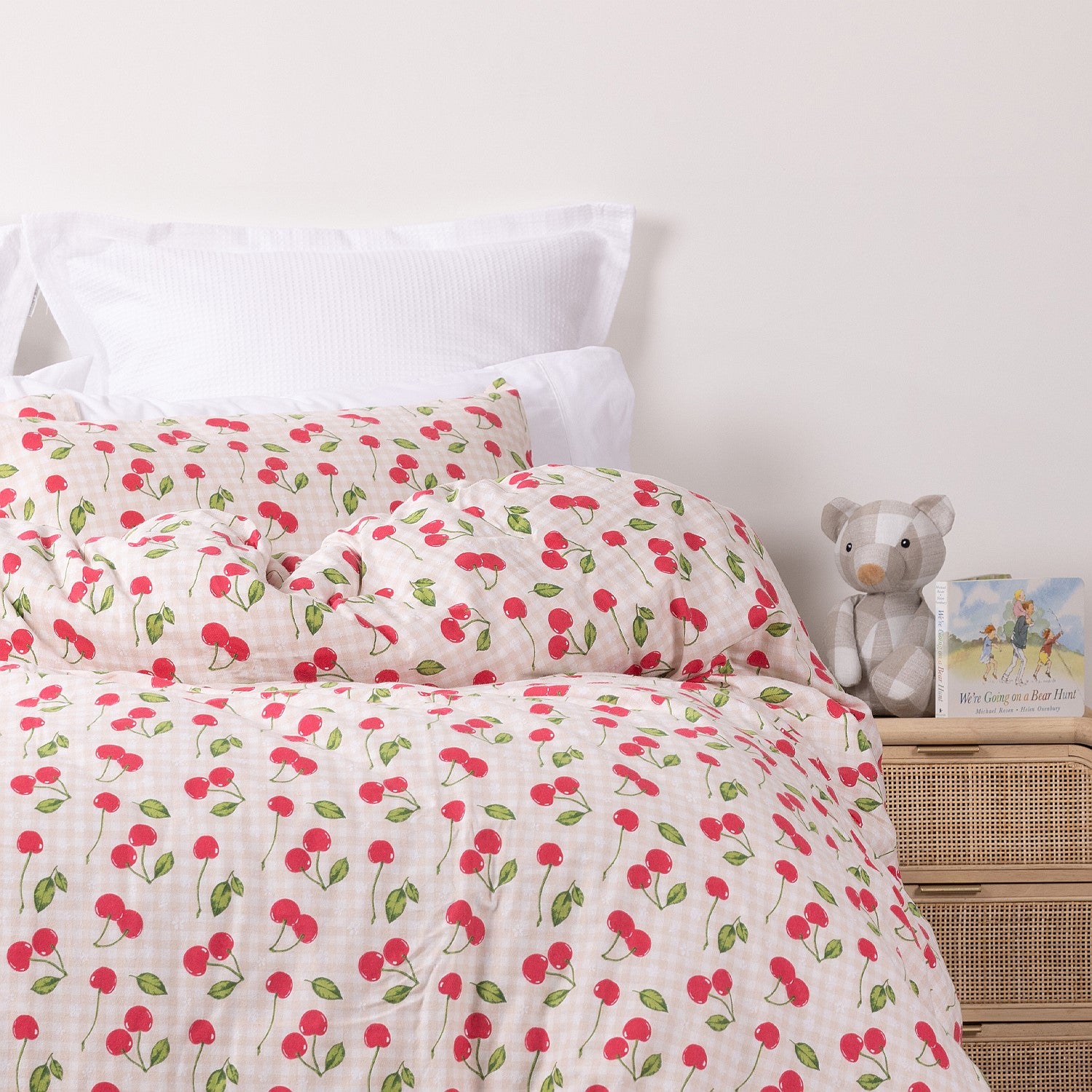 Close up of kids red strawberry print duvet cover set styled on a white bed in a neutral bedroom.