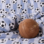 Soccer ball print kids duvet cover set styled with a brown toy ball on the bed.
