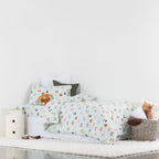 Children's bedroom with a bed featuring animal-patterned bedding and stuffed toys.