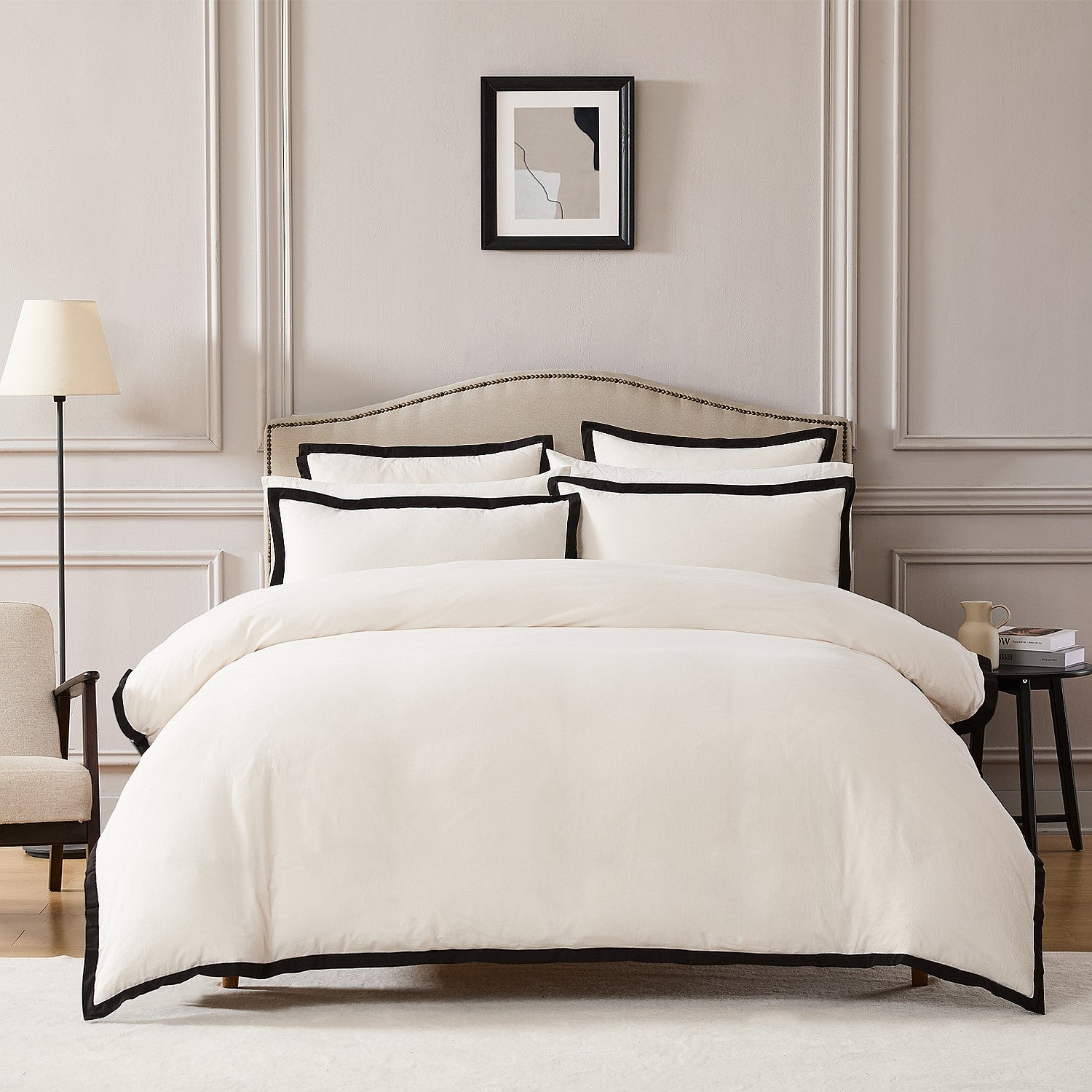 Neatly made bed with white bedding and black trim in a bedroom setting.