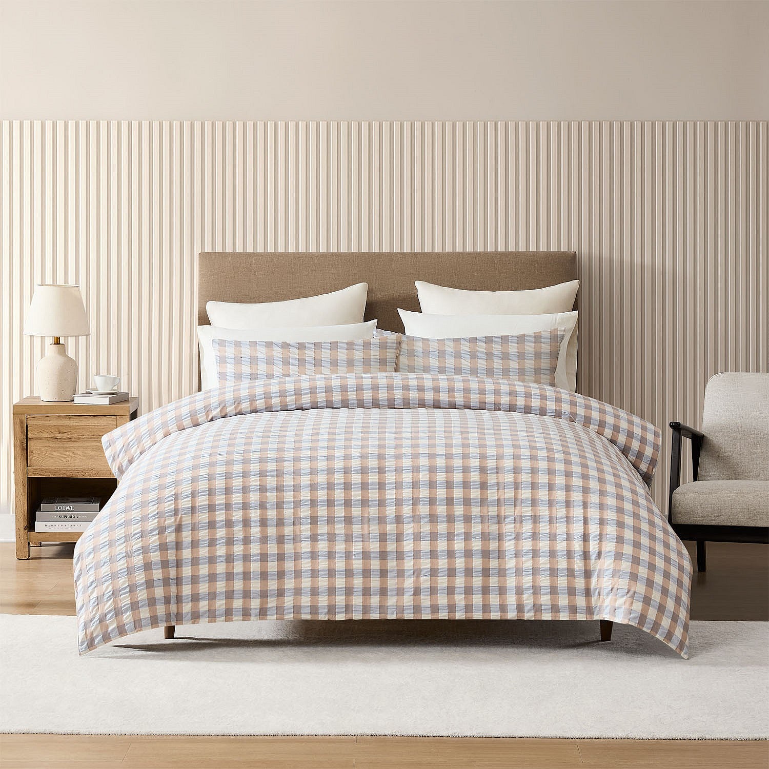 Bed with plaid bedding in a bedroom setting with striped wallpaper.