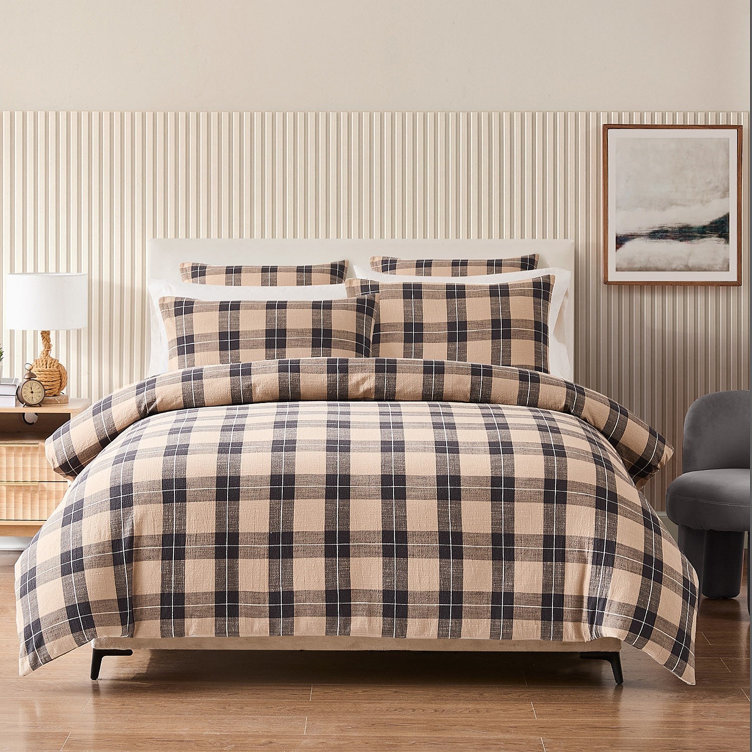 Plaid bedding set on a bed in a bedroom with striped wallpaper and a lamp.