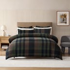 Plaid bedding set on a bed in a bedroom with striped wallpaper and a lamp.