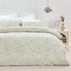Bed with green leaf-patterned bedding in a bedroom setting.