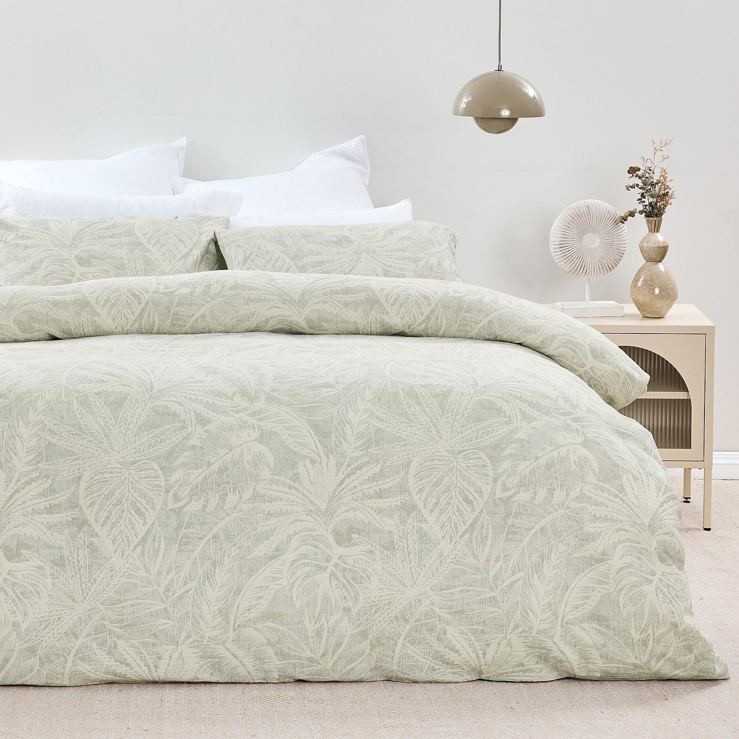 Bed with green leaf-patterned bedding in a bedroom setting.