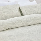 Light gray textured bedding set on a bed with white pillows.