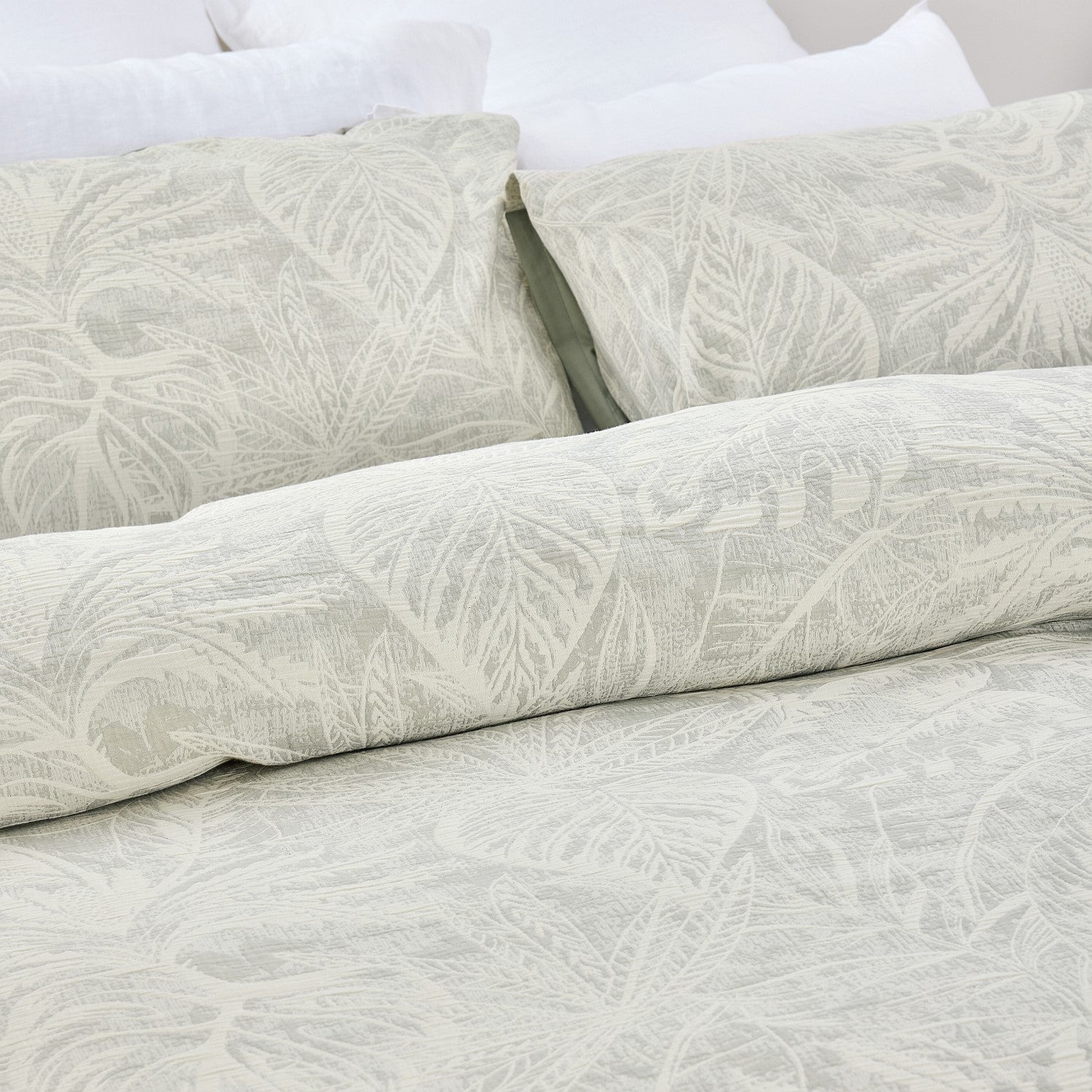 Light gray textured bedding set on a bed with white pillows.