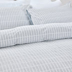Gray striped bedding set on a bed with pillows.