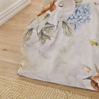 Floral-patterned comforter on a bed with a wooden floor and rug in the background