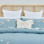 Blue floral bedding set on a bed with a wooden headboard.