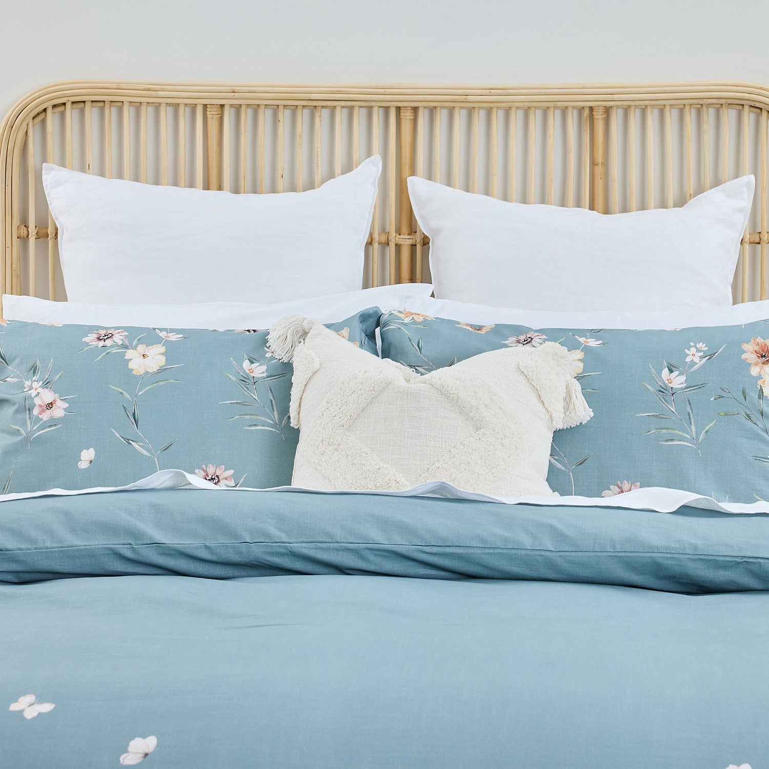 Blue floral bedding set on a bed with a wooden headboard.