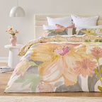 Floral bedding set on a bed in a bedroom with a side table and lamp.