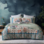 Floral patterned quilt and pillows on a bed with a dark textured wall in the background.
