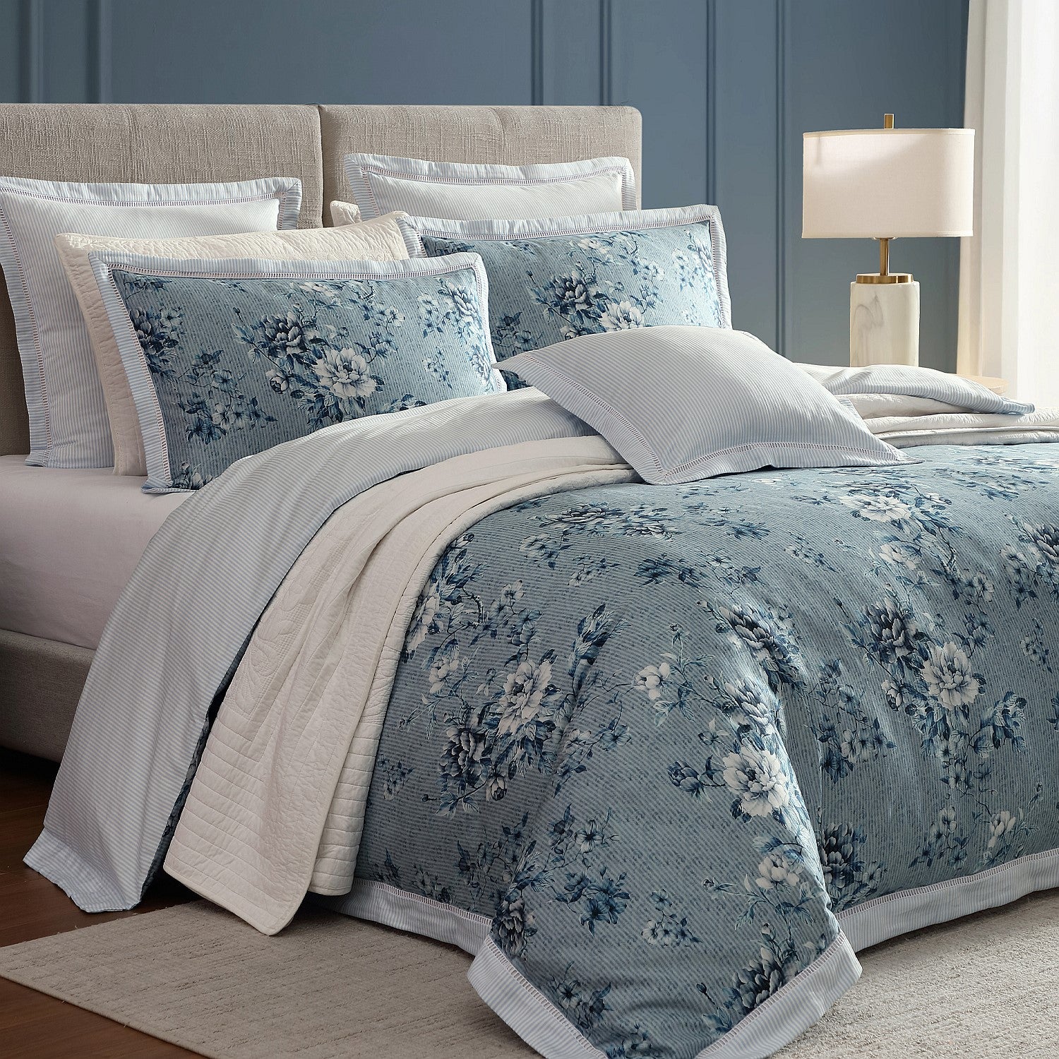 Floral bedding set on a bed with a lamp in the background