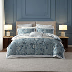 Bedroom with floral bedding, nightstands, and lamps against a blue paneled wall.