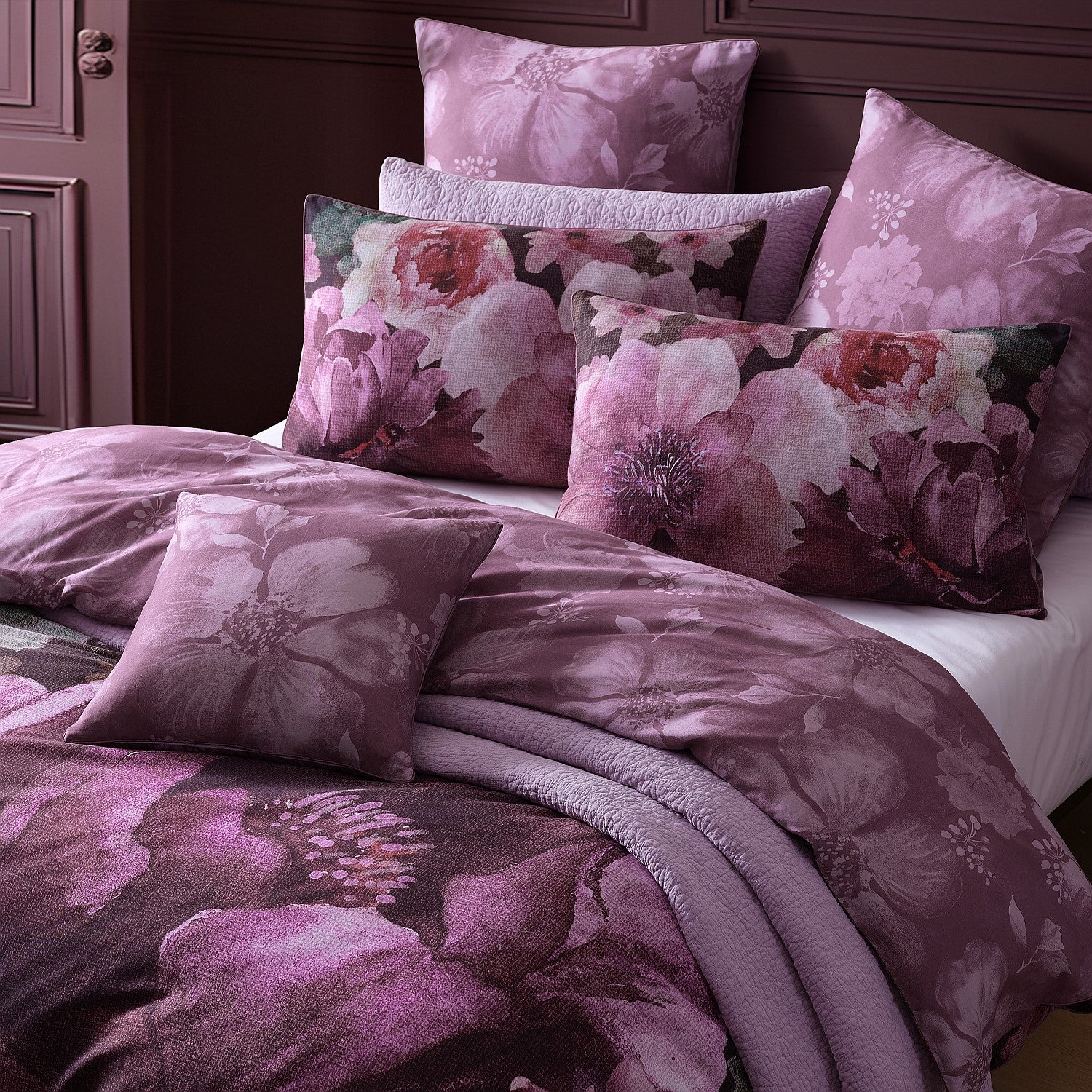 Floral patterned bedding set on a bed with a dark wooden headboard.