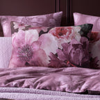 Floral patterned pillows and bedding on a bed with a dark headboard.
