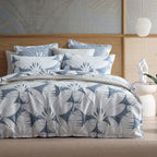 Bed with blue and gray leaf-patterned bedding in a bedroom setting.