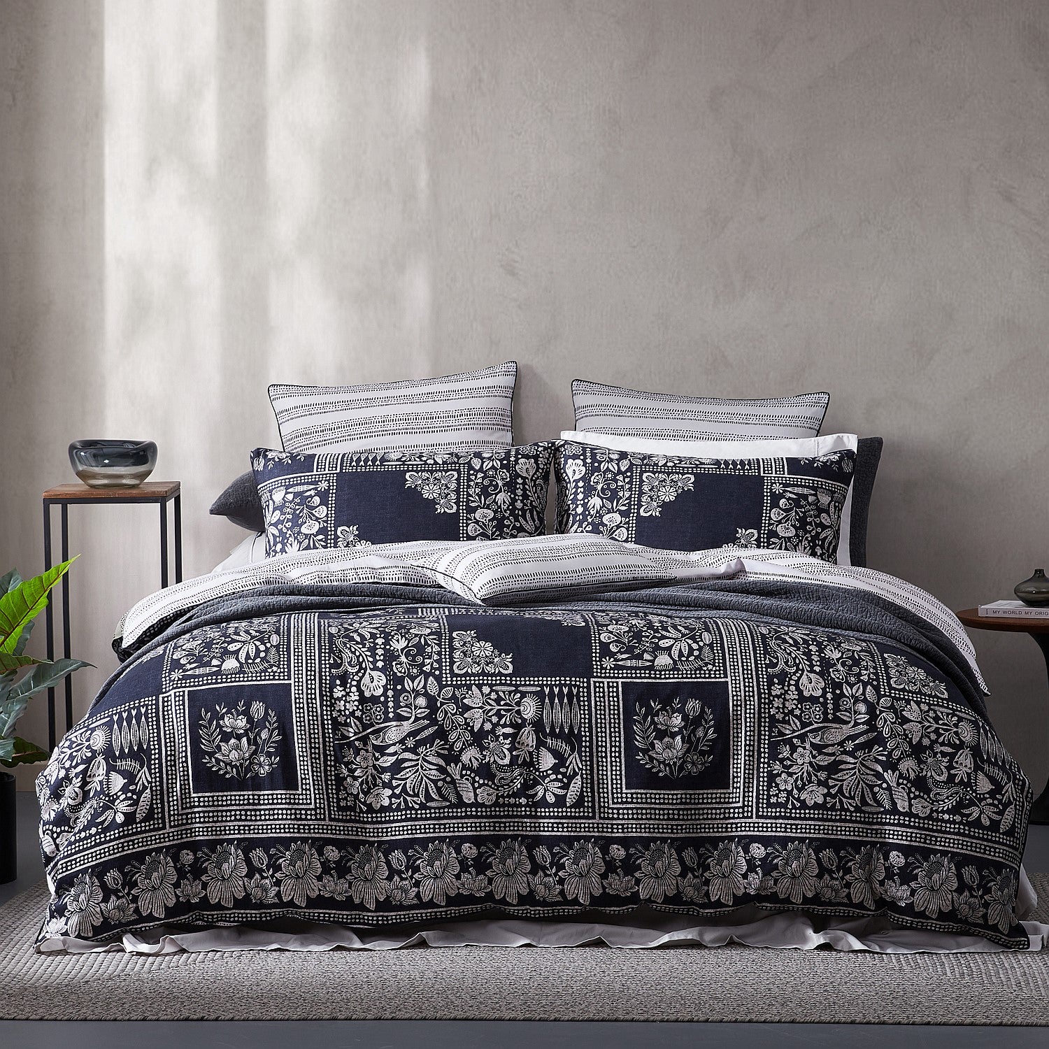 Bed with floral patterned comforter and pillows against a neutral wall.