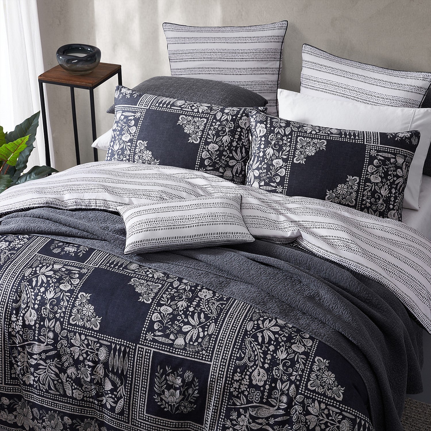 Bed with patterned bedding and pillows in a bedroom setting