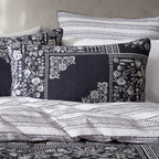 Decorative pillows with black and white patterns on a bed with matching bedding.