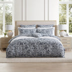 Bedroom with floral-patterned bedding on a bed, flanked by two nightstands with lamps.