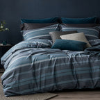 Bed with striped bedding and pillows against a dark wall