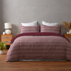 Bed with plaid bedding in a bedroom setting with a gray wall and wooden nightstands.