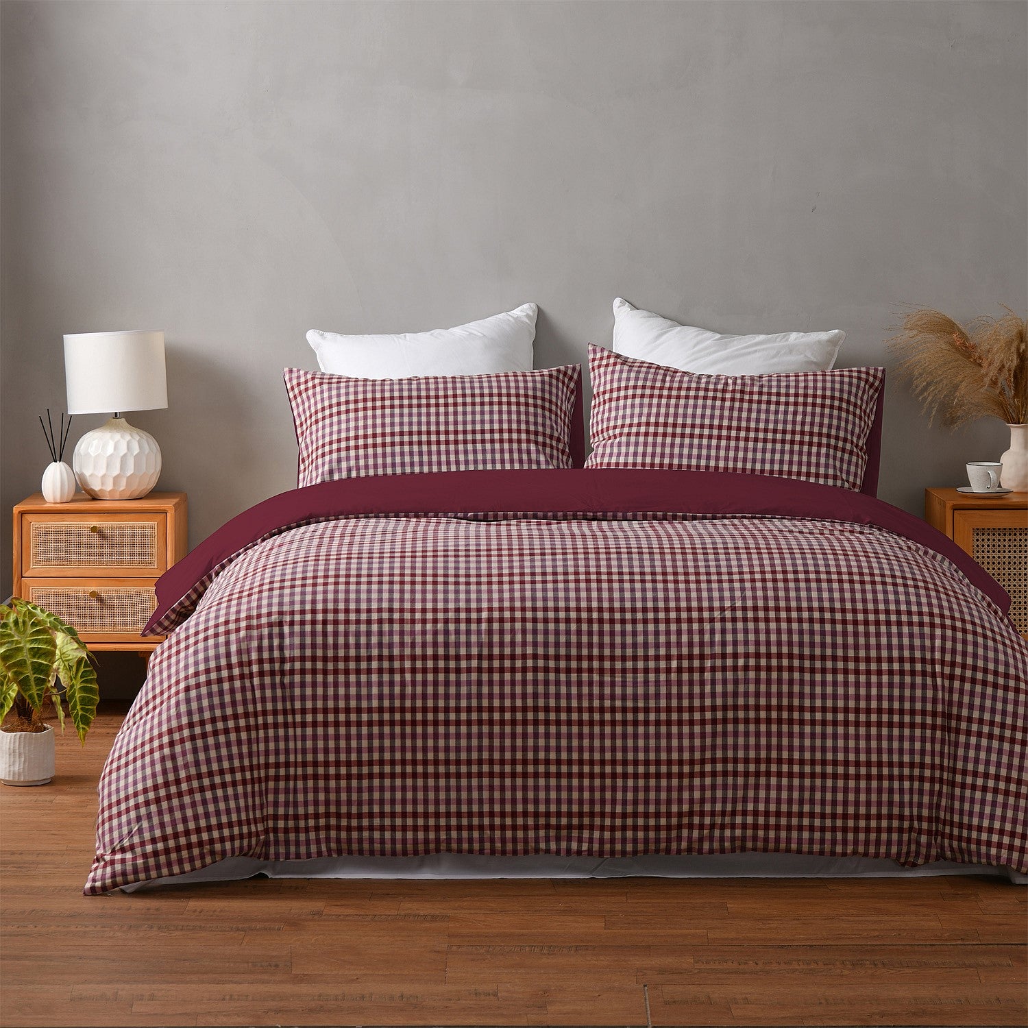 Bed with plaid bedding in a bedroom setting with a gray wall and wooden nightstands.