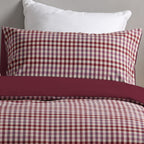 Red and white checkered pillowcases on a bed with a plain background