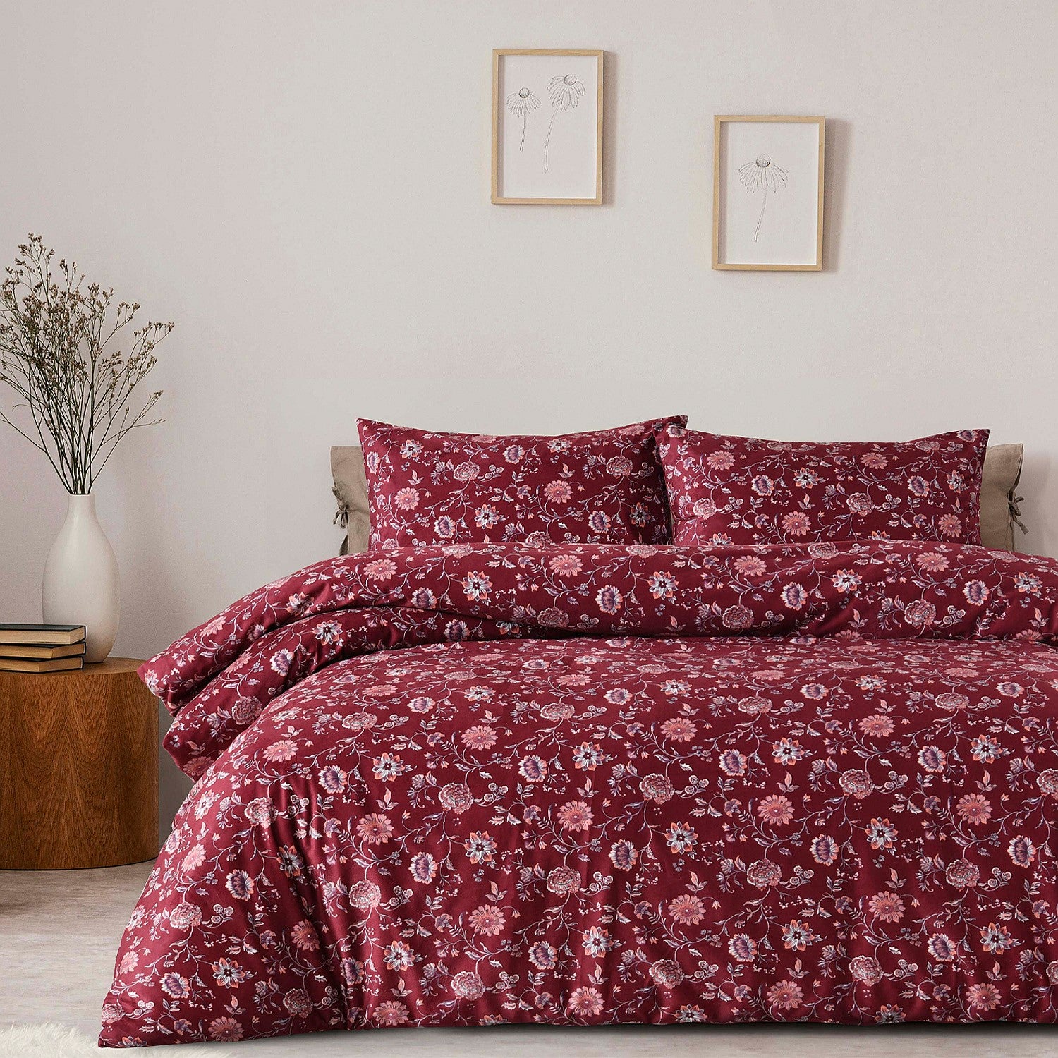 Floral patterned bedding set on a bed in a bedroom with a side table and decor.