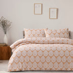 Patterned bedspread set on a bed in a bedroom with side table and decor.