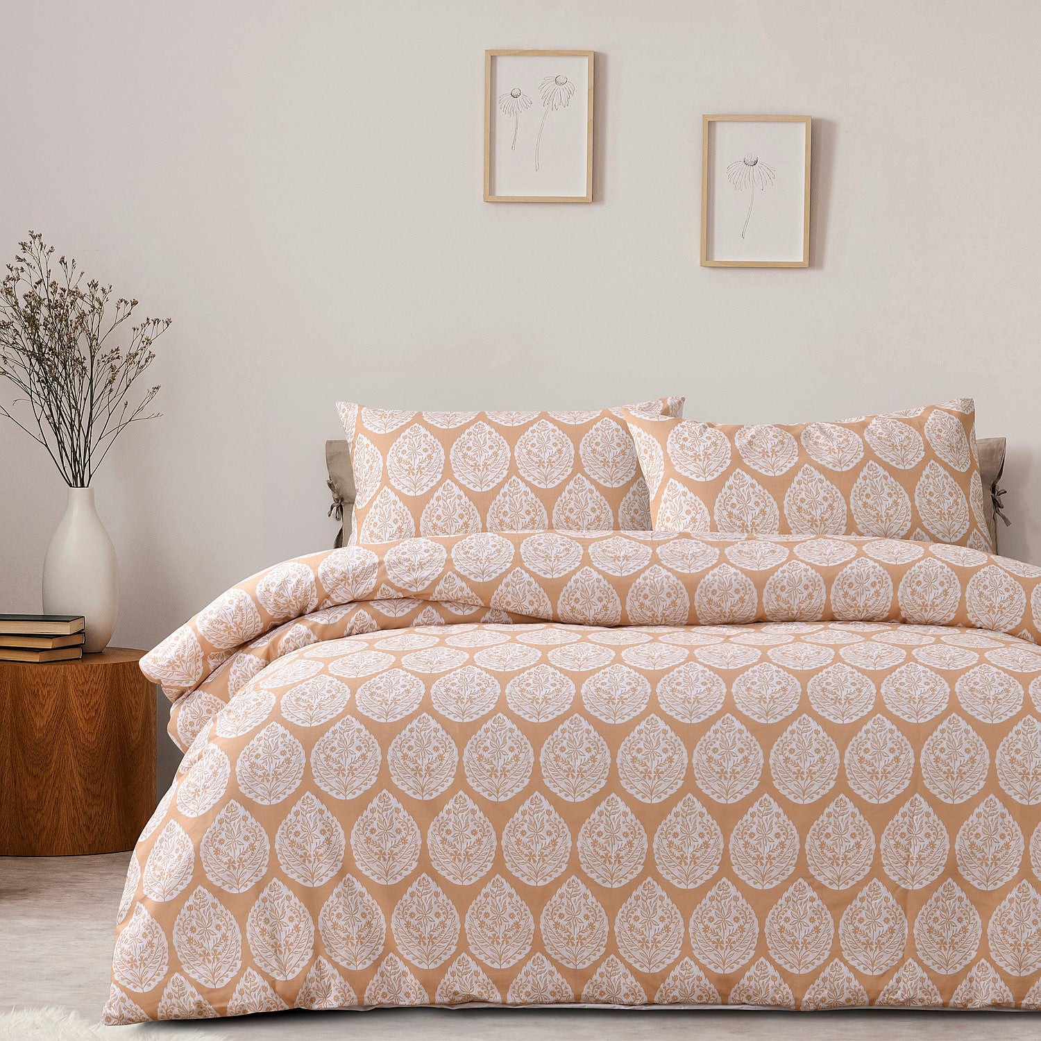 Patterned bedspread set on a bed in a bedroom with side table and decor.