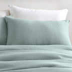Teal textured bedding set with pillows on a neutral background