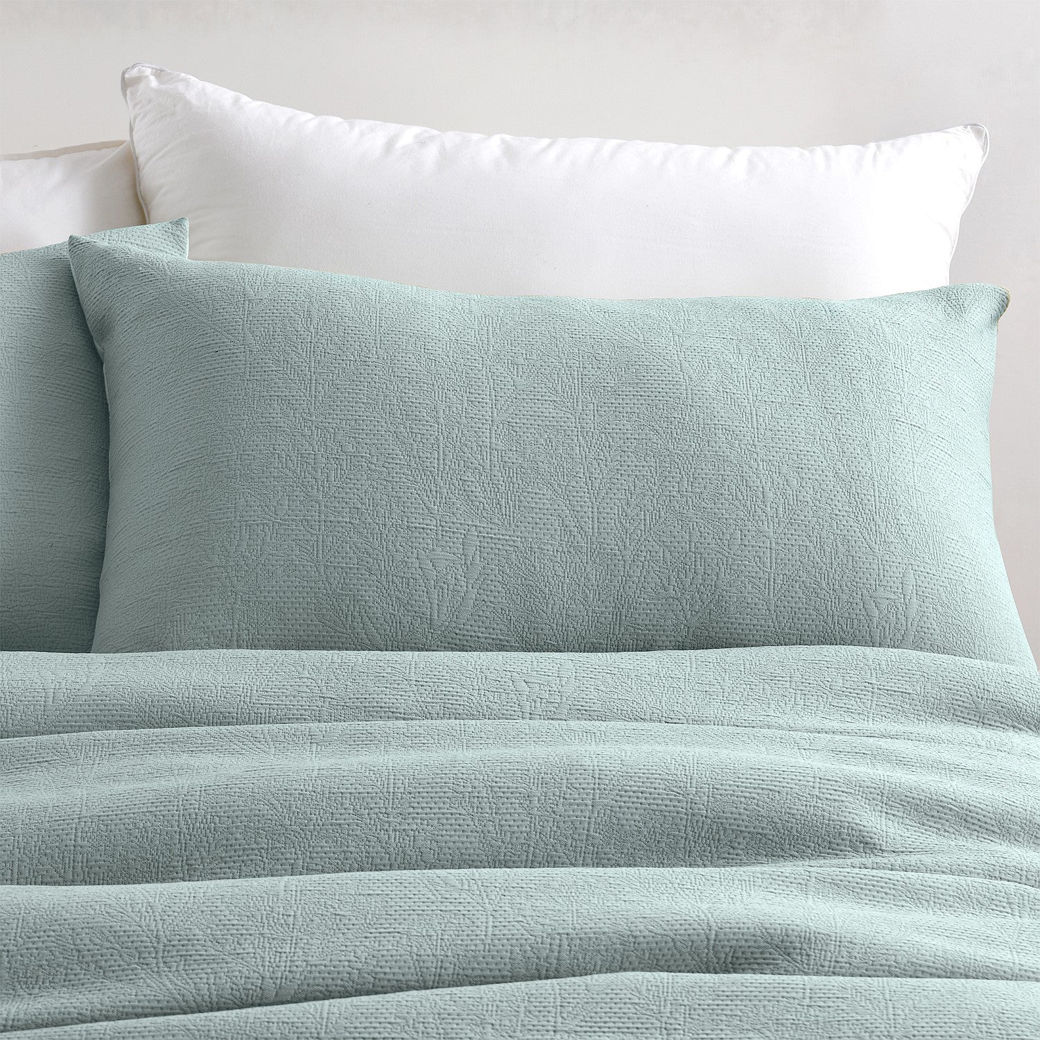 Teal textured bedding set with pillows on a neutral background