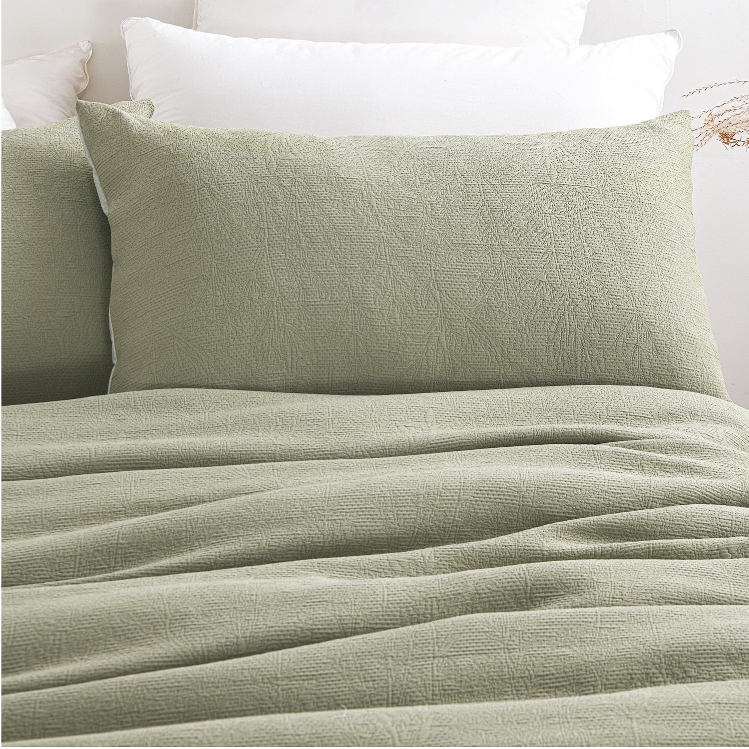 Green textured comforter on a bed with white pillows