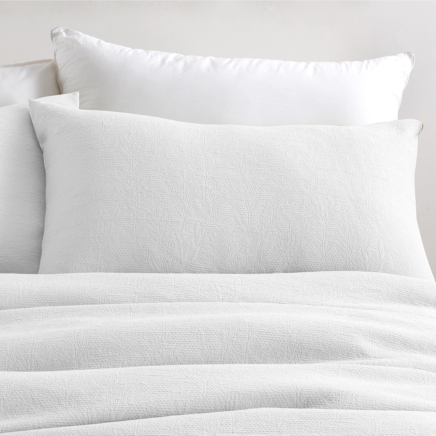 White bedding set with pillows on a neutral background