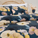 Floral bedding set with navy background on a bed with white pillows.