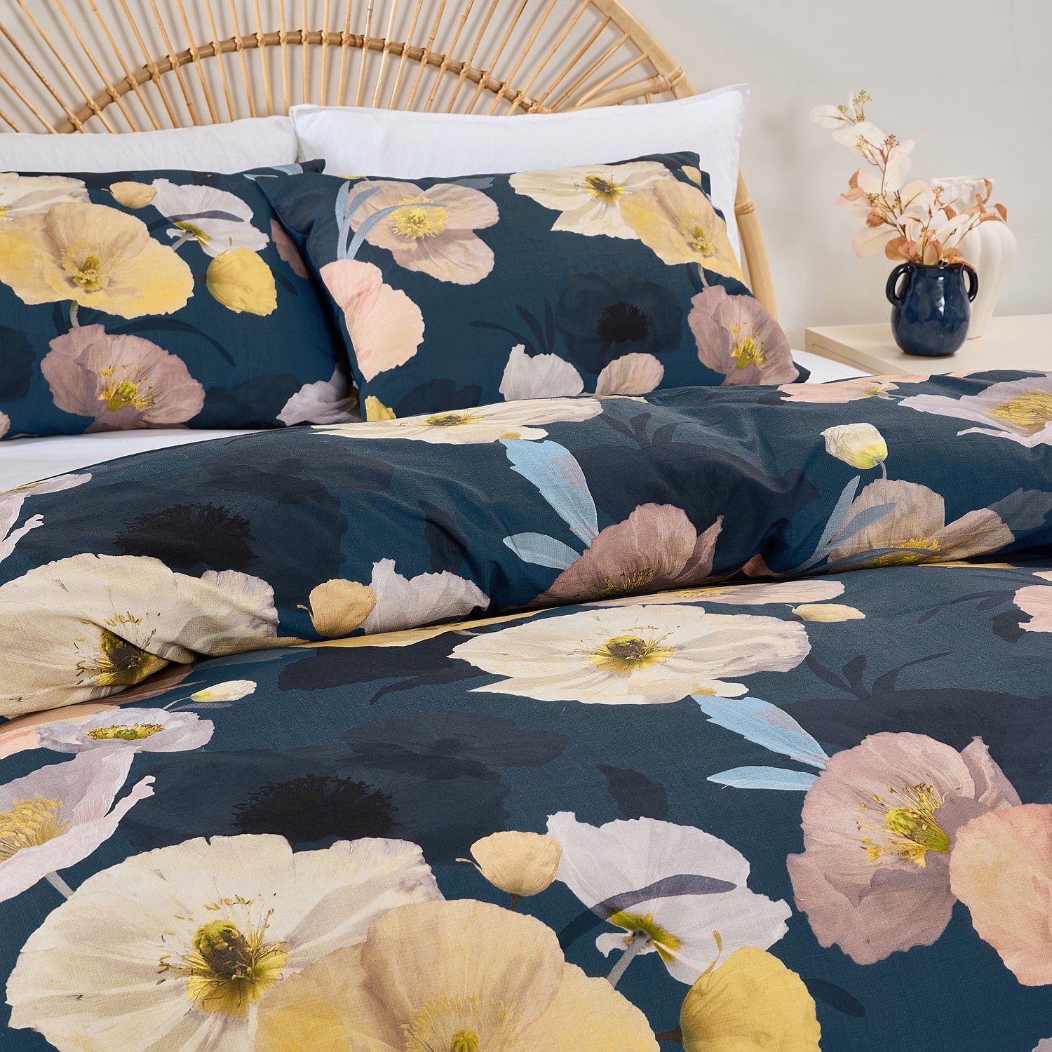 Floral bedding set with navy background on a bed with white pillows.