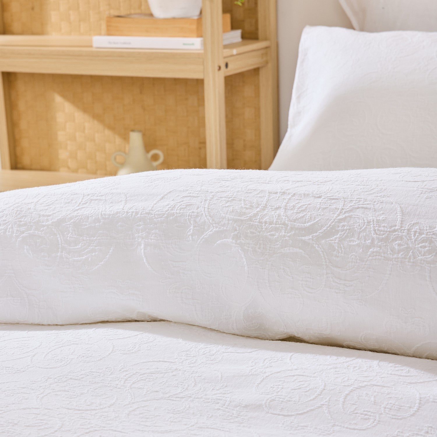White textured duvet cover on a bed with a wooden headboard and decorative items.