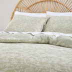 Bed with green floral bedding and a wicker headboard.