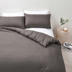Bed with brown bedding and white pillows in a minimalistic room.