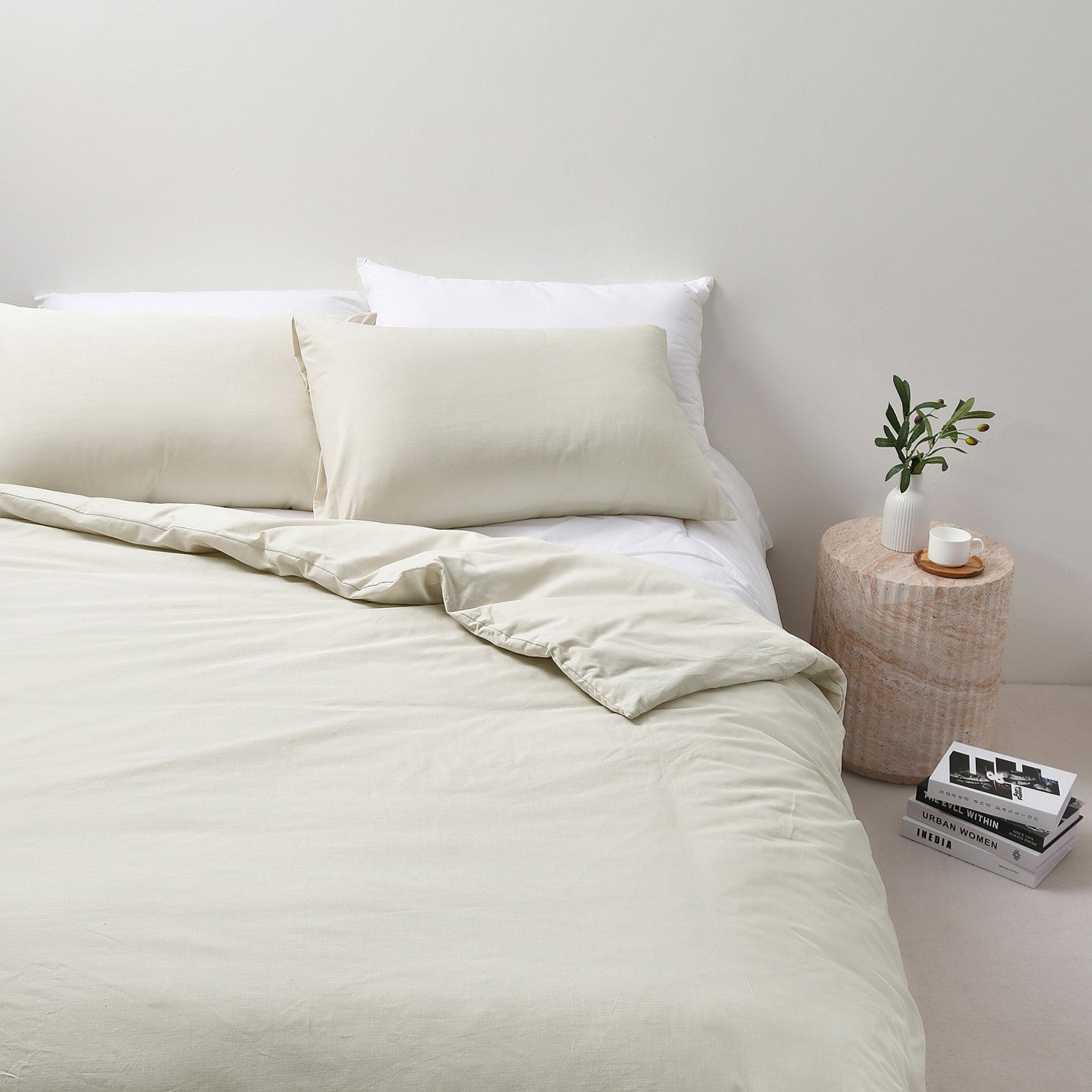 Neatly made bed with beige bedding in a minimalistic bedroom setting.