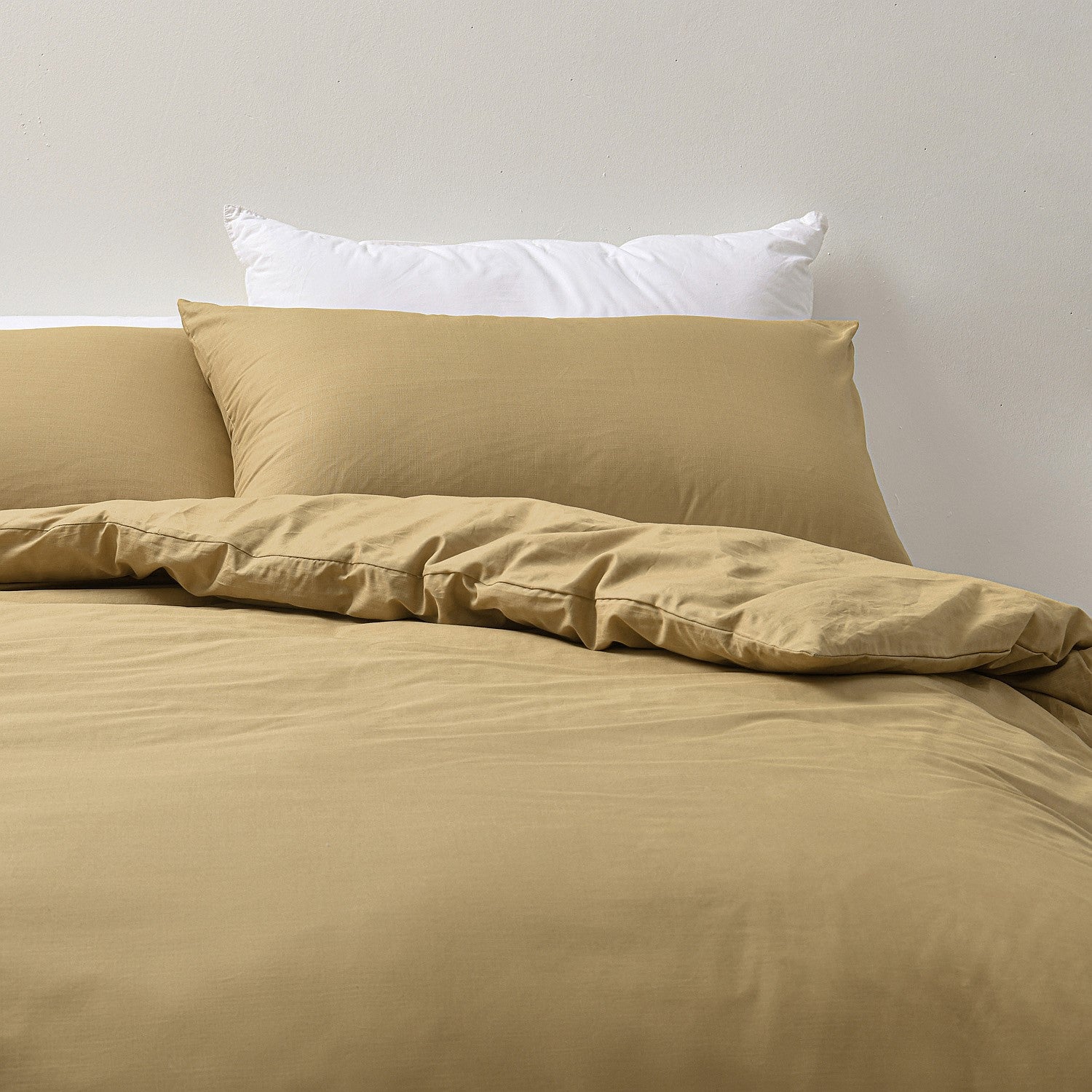 Beige bedding set with white pillows on a neutral background