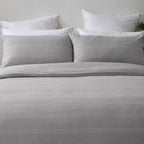 Gray bedding set with white pillows on a neutral background