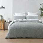 Bed with green quilt and pillows in a bedroom setting