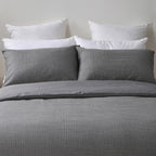 Gray checkered bedding set with white pillows on a neutral background